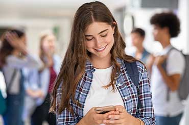 Young girl with a great smile texting on her phone