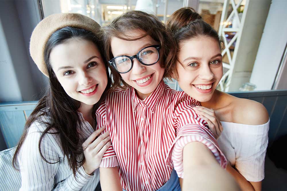 three teenage girls smiling and posing